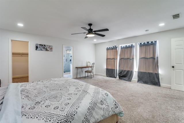 bedroom featuring a spacious closet, light carpet, and ceiling fan