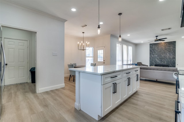 kitchen featuring decorative light fixtures, light hardwood / wood-style flooring, a center island, and white cabinets