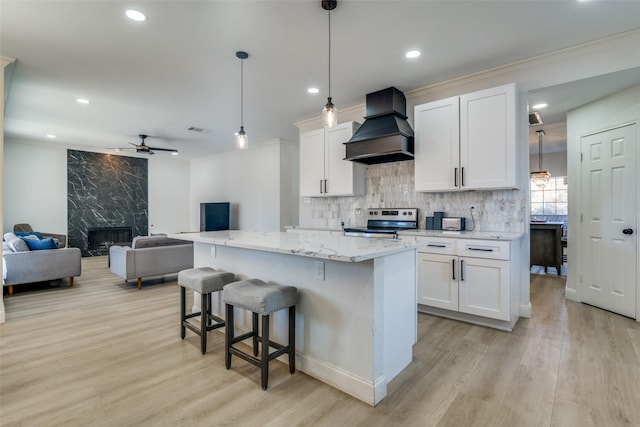 kitchen featuring stainless steel electric range, pendant lighting, custom exhaust hood, and white cabinets