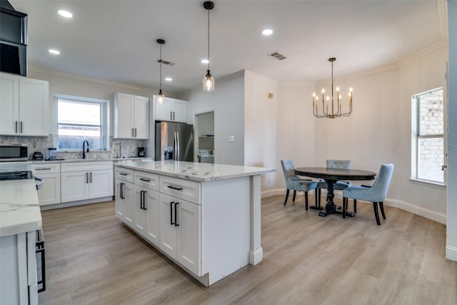 kitchen featuring a center island, hanging light fixtures, stainless steel appliances, decorative backsplash, and white cabinets