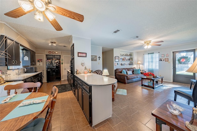 kitchen with sink, ceiling fan, black fridge, and a textured ceiling