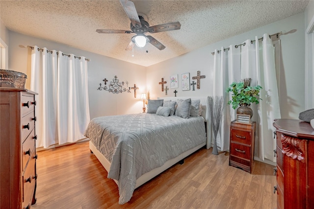 bedroom with a textured ceiling, light wood-type flooring, and ceiling fan