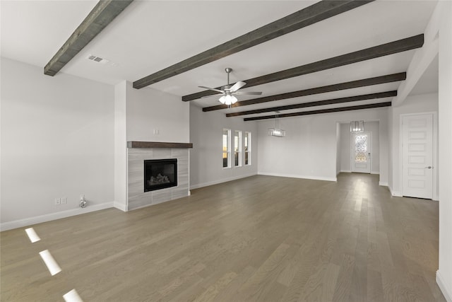 1057 Fleetwood Dr, Justin, TX 76247 - unfurnished living room featuring beamed ceiling, ceiling fan, wood-type flooring, and a tile fireplace