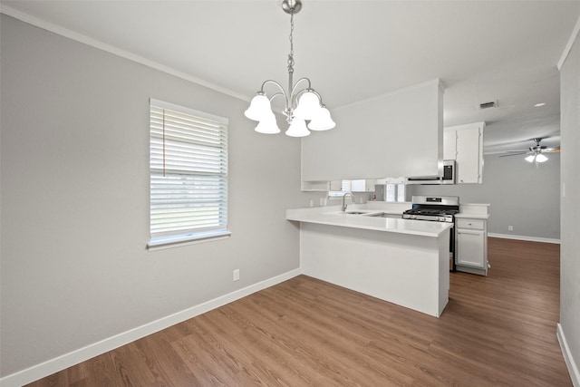 kitchen with sink, kitchen peninsula, decorative light fixtures, white cabinetry, and stainless steel appliances