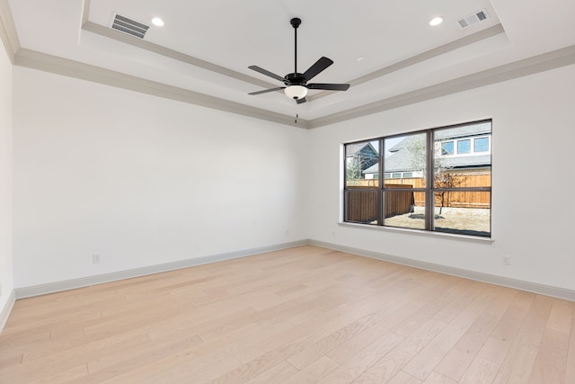 unfurnished room featuring a raised ceiling, ceiling fan, and light wood-type flooring