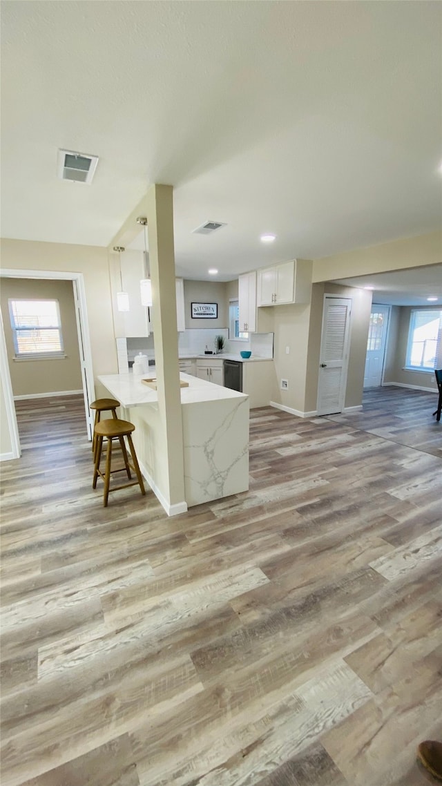 kitchen with decorative light fixtures, plenty of natural light, white cabinetry, and light hardwood / wood-style flooring