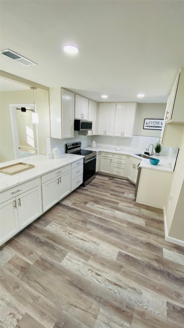 kitchen featuring white cabinets, hanging light fixtures, light wood-type flooring, and appliances with stainless steel finishes