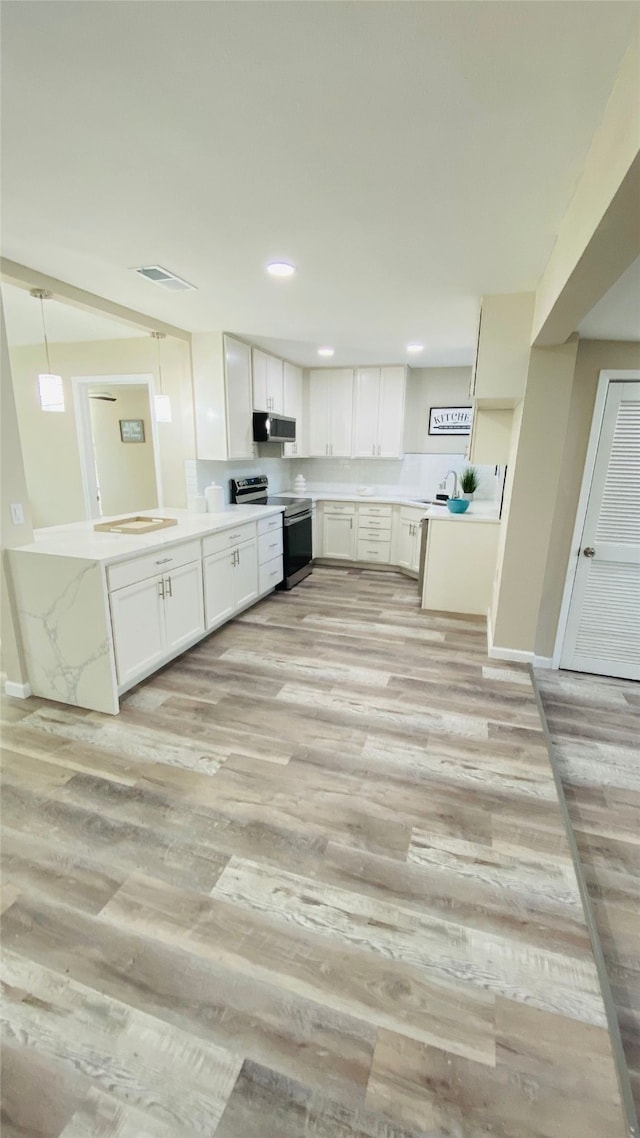 kitchen with kitchen peninsula, appliances with stainless steel finishes, light wood-type flooring, white cabinetry, and hanging light fixtures