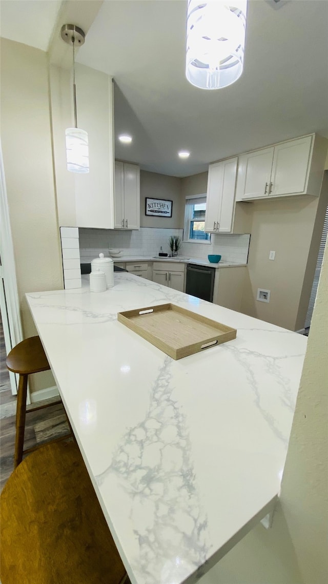 kitchen featuring kitchen peninsula, black dishwasher, white cabinetry, and hanging light fixtures