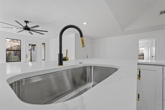 details featuring ceiling fan, light stone countertops, white cabinetry, and sink