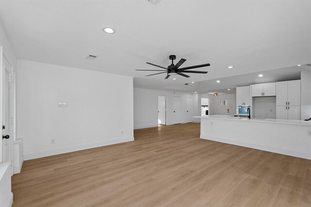 unfurnished living room with light hardwood / wood-style floors, ceiling fan, and sink