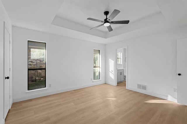 unfurnished room featuring light hardwood / wood-style flooring, a raised ceiling, and ceiling fan