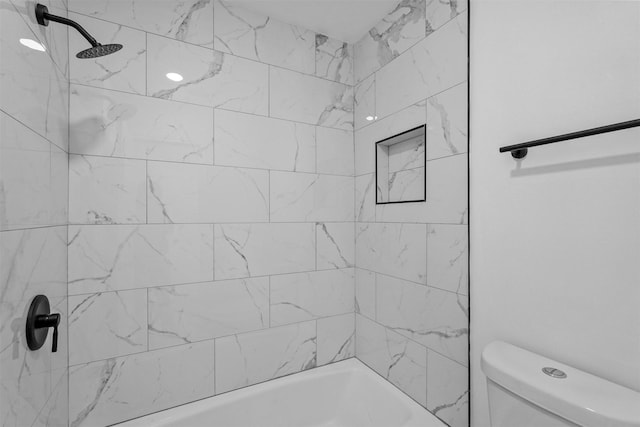 bathroom featuring toilet and tiled shower / bath