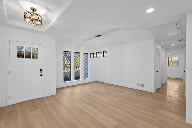 entryway with a raised ceiling, light wood-type flooring, and a wealth of natural light