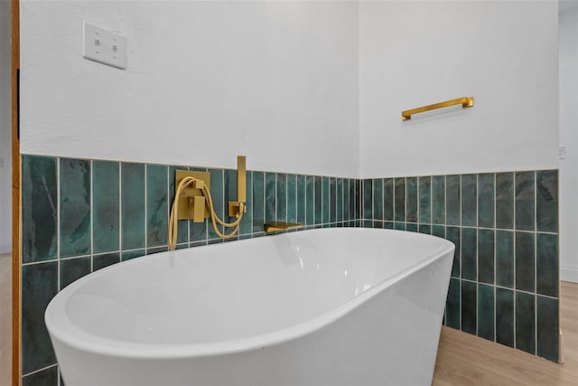 bathroom featuring a tub to relax in, sink, wood-type flooring, and tile walls