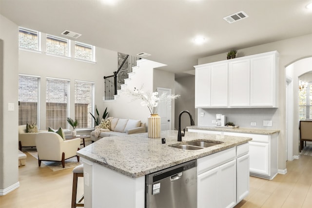 2053 Barx Dr, Little Elm, TX 75068 - kitchen featuring stainless steel dishwasher, a sink, an island with sink, white cabinets, and arched walkways