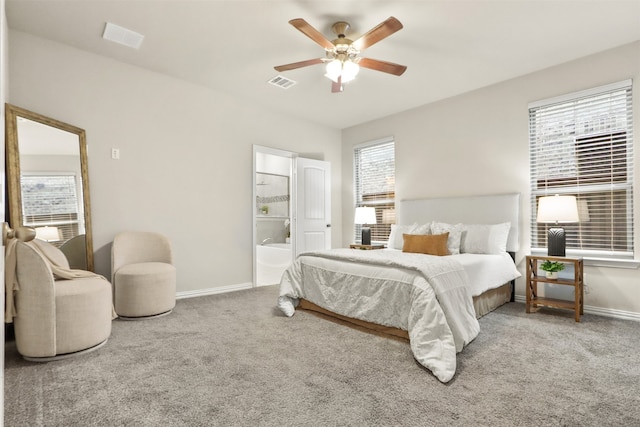 carpeted bedroom with multiple windows, ceiling fan, and ensuite bath