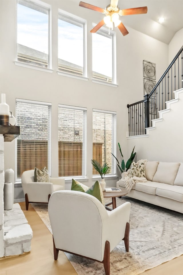 living room with a high ceiling, a wealth of natural light, and light hardwood / wood-style flooring