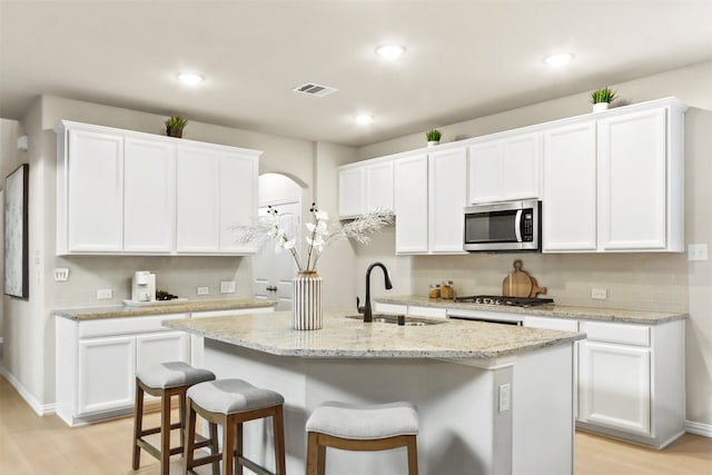 kitchen with sink, white cabinetry, stainless steel appliances, and an island with sink