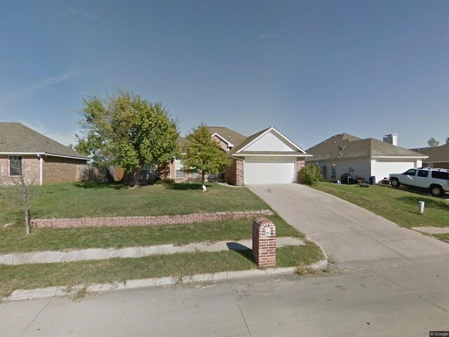 ranch-style house featuring a front yard and a garage