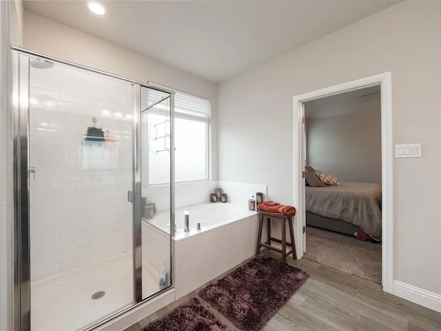 bathroom featuring wood-type flooring and separate shower and tub