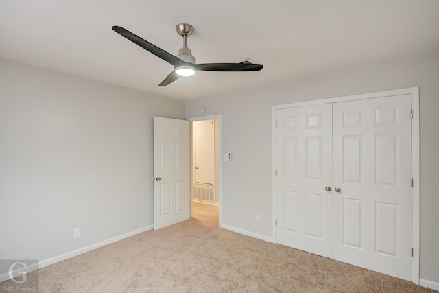 unfurnished bedroom with ceiling fan, a closet, and light carpet