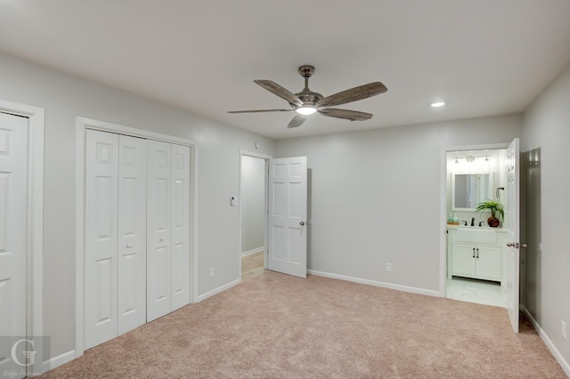 unfurnished bedroom featuring two closets, sink, ceiling fan, connected bathroom, and light colored carpet