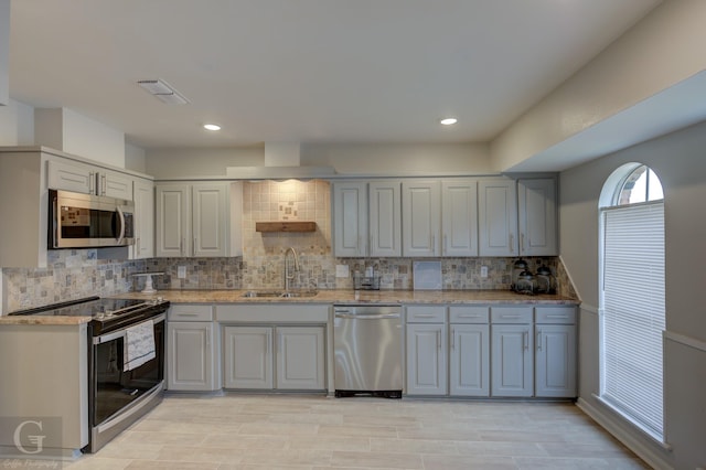 kitchen featuring gray cabinetry, light stone countertops, sink, tasteful backsplash, and appliances with stainless steel finishes