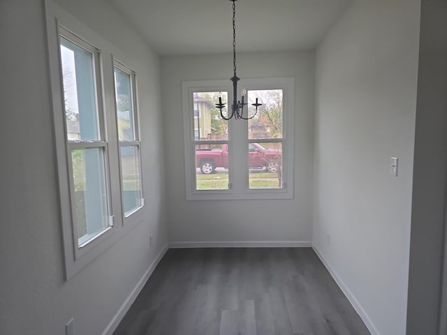 unfurnished dining area featuring dark hardwood / wood-style floors and a chandelier