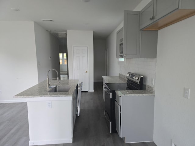 kitchen featuring gray cabinetry, sink, an island with sink, appliances with stainless steel finishes, and dark hardwood / wood-style flooring