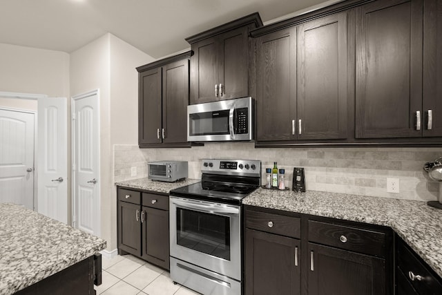 kitchen with light tile patterned flooring, stainless steel appliances, dark brown cabinets, and backsplash