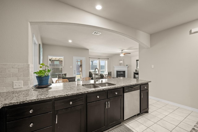 kitchen featuring sink, stainless steel dishwasher, light tile patterned floors, ceiling fan, and light stone counters