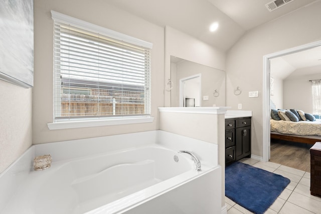 bathroom featuring tile patterned floors, vanity, a tub to relax in, and vaulted ceiling