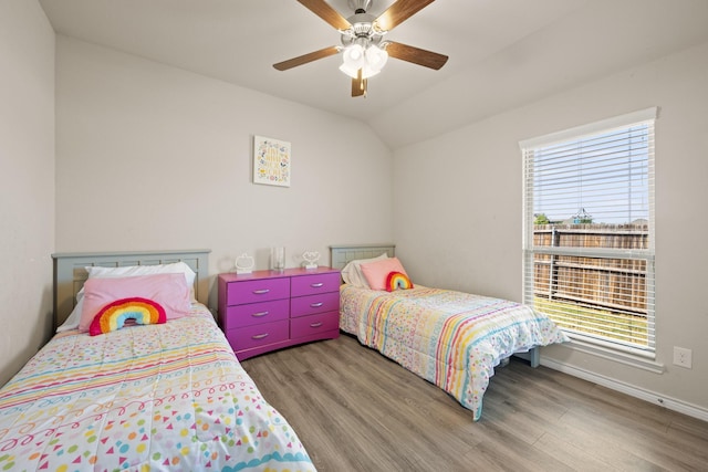 bedroom featuring multiple windows, ceiling fan, wood-type flooring, and vaulted ceiling