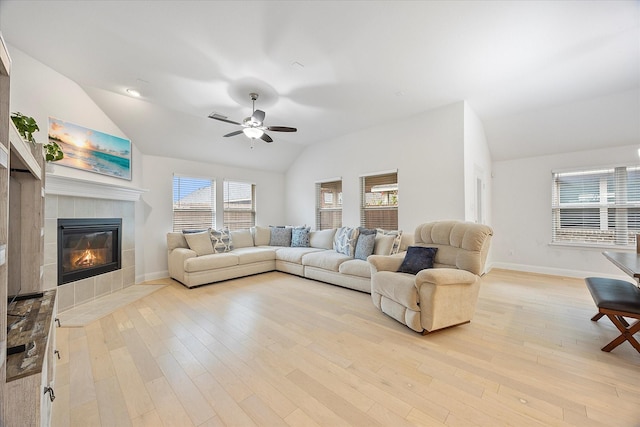 living room with a fireplace, vaulted ceiling, ceiling fan, and light wood-type flooring