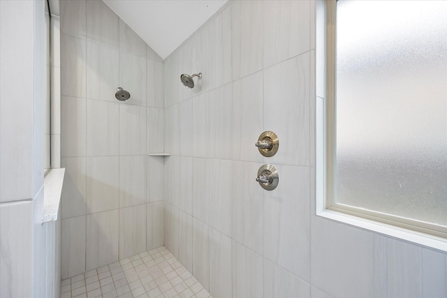 bathroom featuring a tile shower and vaulted ceiling