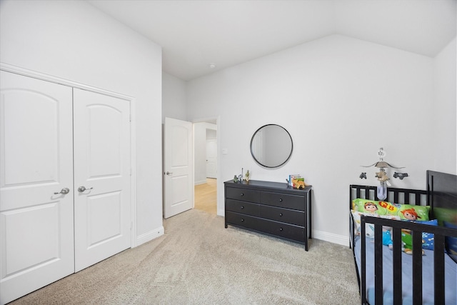 bedroom featuring light carpet, a closet, and lofted ceiling