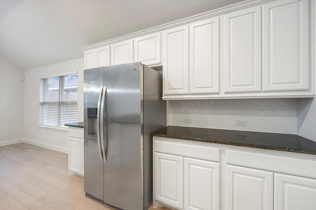 kitchen featuring dark stone counters, white cabinets, decorative backsplash, light wood-type flooring, and stainless steel fridge with ice dispenser