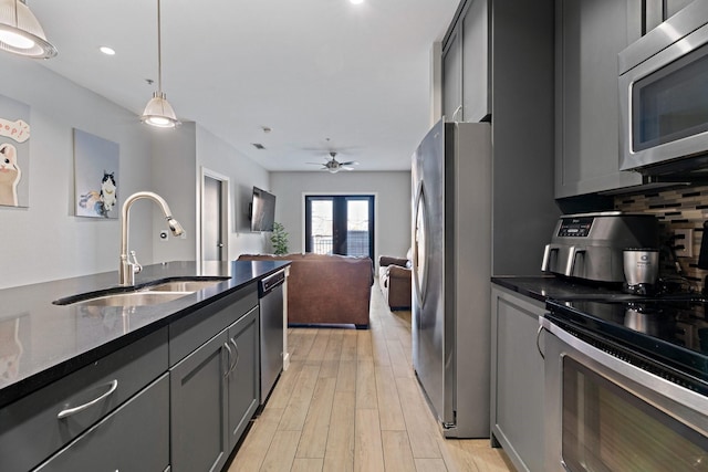 kitchen featuring french doors, stainless steel appliances, sink, dark stone countertops, and hanging light fixtures