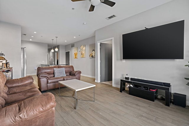 living room with ceiling fan, light hardwood / wood-style floors, and sink