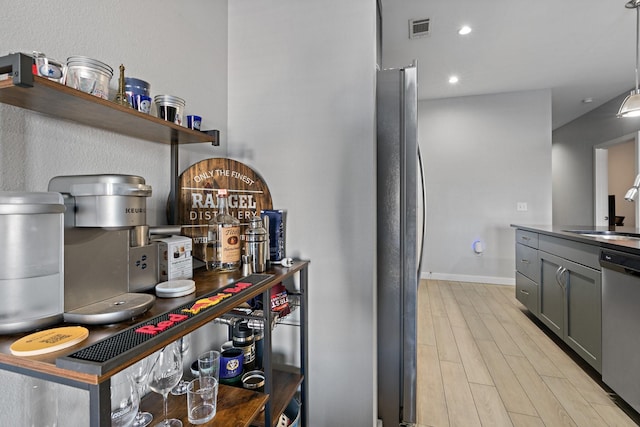 bar with appliances with stainless steel finishes, light wood-type flooring, gray cabinetry, sink, and pendant lighting