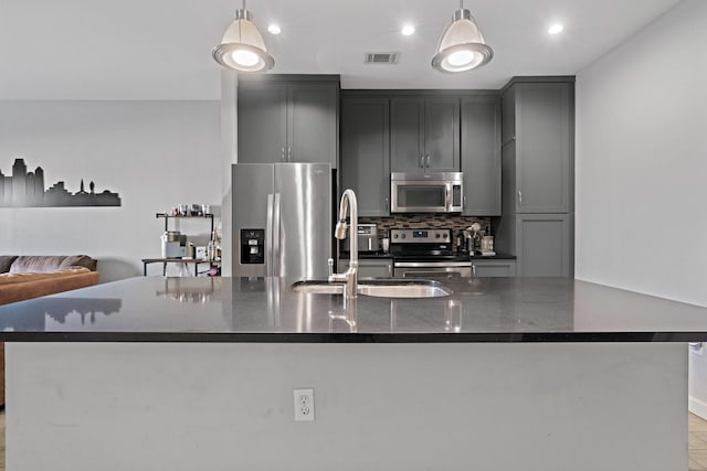 kitchen featuring tasteful backsplash, dark stone countertops, pendant lighting, and appliances with stainless steel finishes