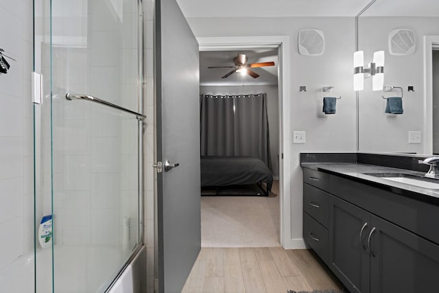 bathroom with ceiling fan, bath / shower combo with glass door, vanity, and wood-type flooring