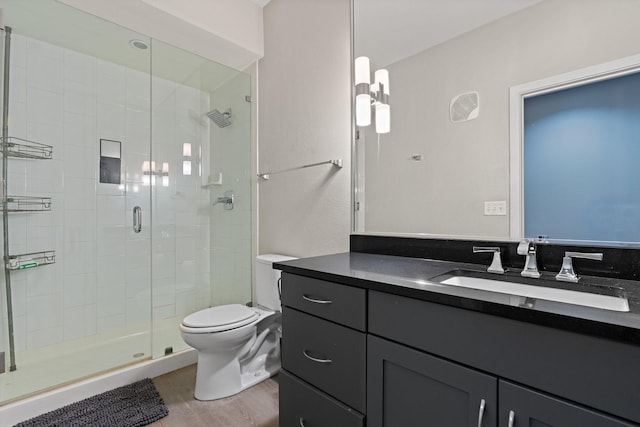 bathroom with hardwood / wood-style floors, vanity, toilet, and a shower with shower door