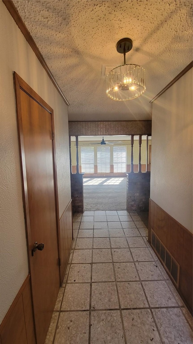 hallway featuring a textured ceiling and ornamental molding