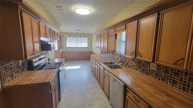 kitchen with backsplash, sink, a textured ceiling, butcher block counters, and stainless steel appliances