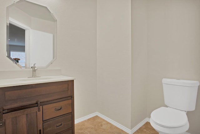 bathroom with toilet, baseboards, and vanity