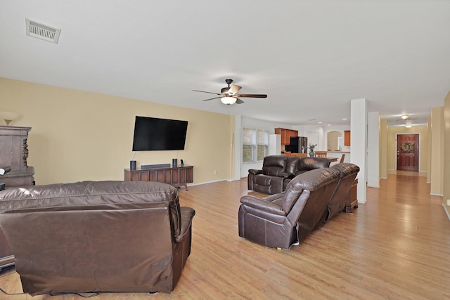 living room with baseboards, light wood-style flooring, visible vents, and a ceiling fan