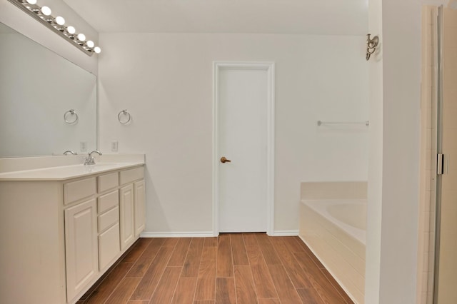 full bath with baseboards, a washtub, wood finished floors, and vanity