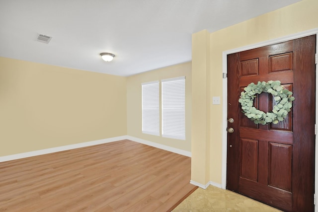 foyer featuring light wood-style flooring, visible vents, and baseboards